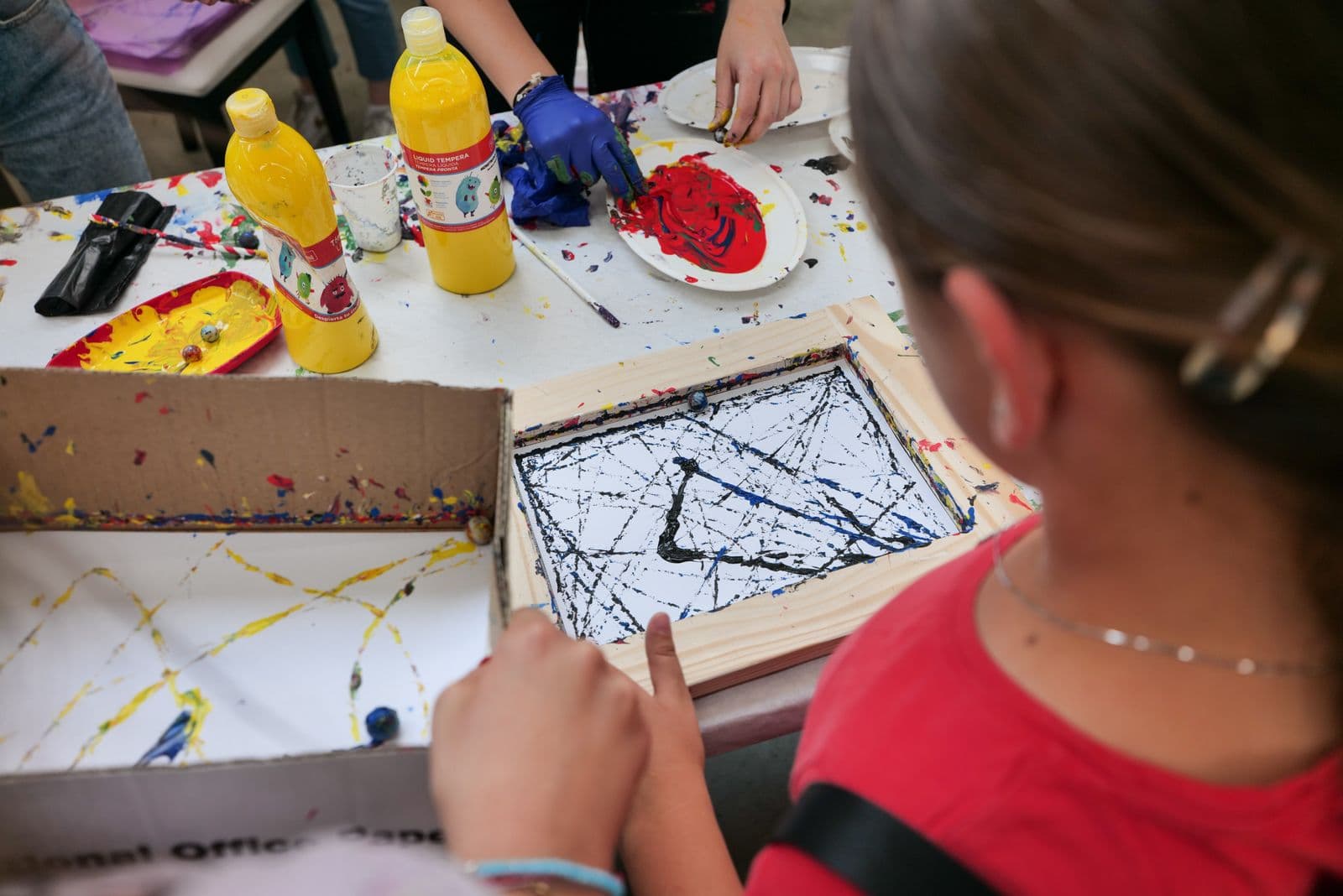 Children creating colorful, hands-on paintings together at an art table.