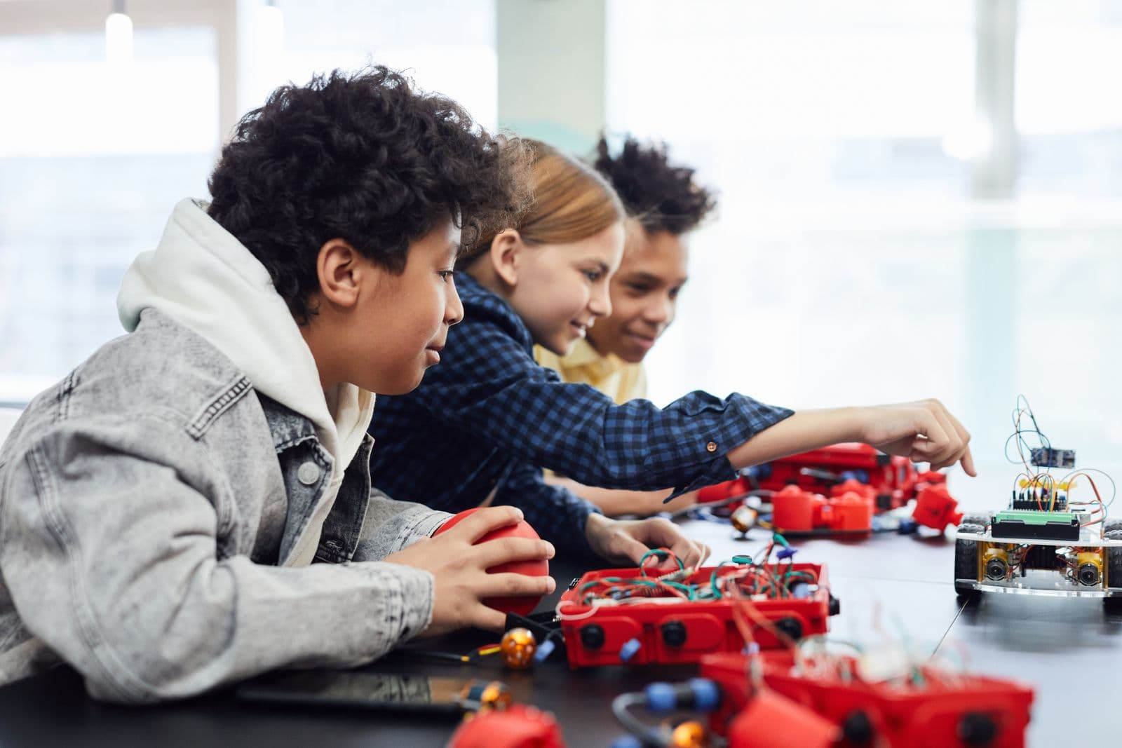 Students building a colorful robotics project together at a classroom table.